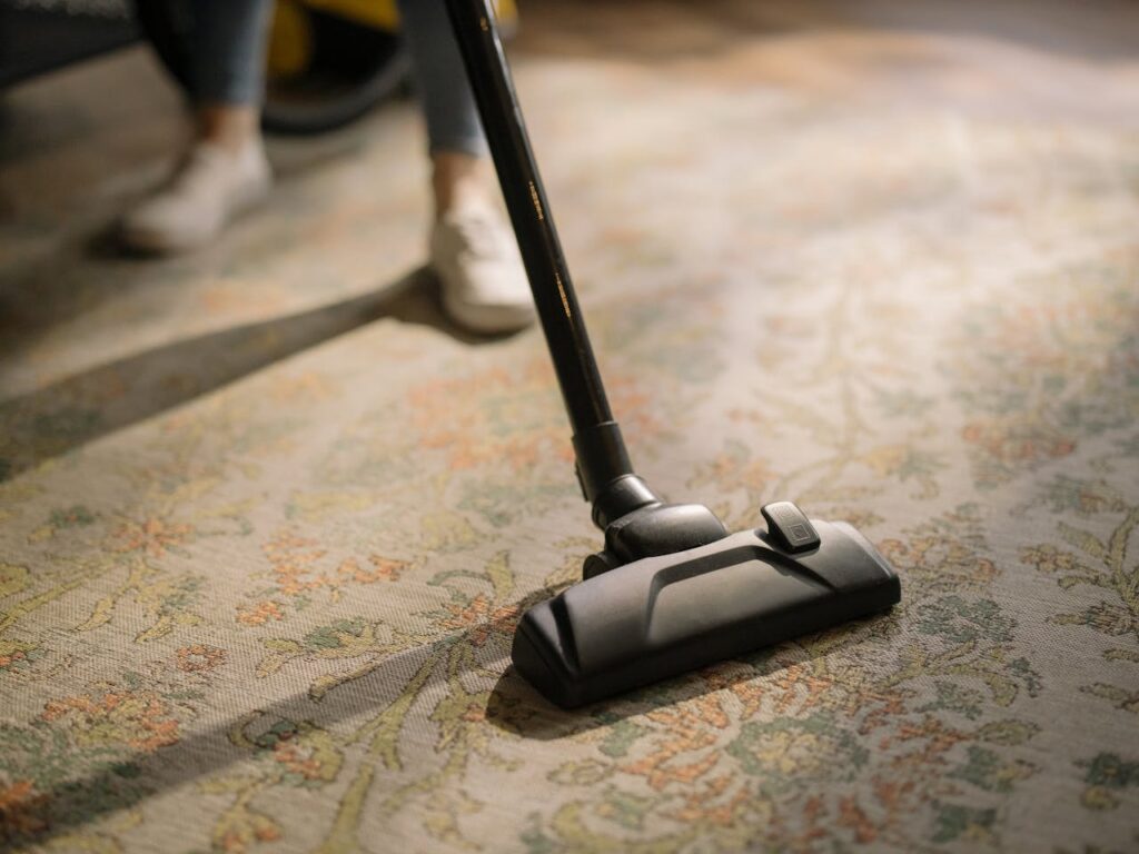 pexels-photo-4107284 Close-up of a vacuum cleaner on a patterned carpet in a sunlit room, capturing a moment of household cleaning.